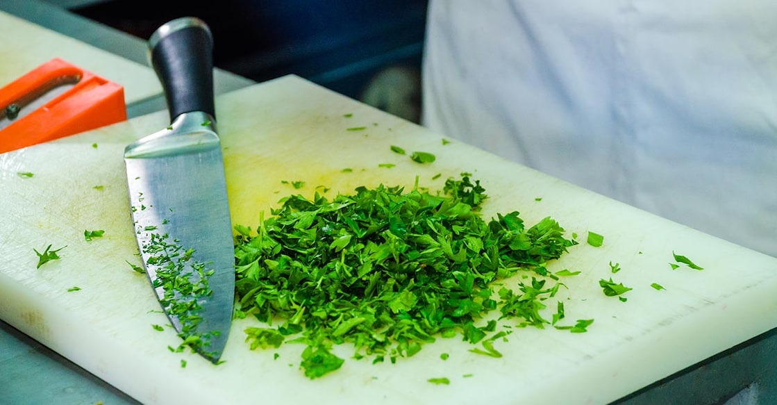 Cutting board Chopped parsley on a white plastic cutting board wit the knife next to it. Photo: Shutterstock/Branimir Dobes