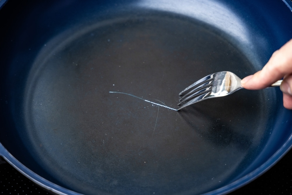 2572692097 Fork scratching the non stick coating on a frying pan