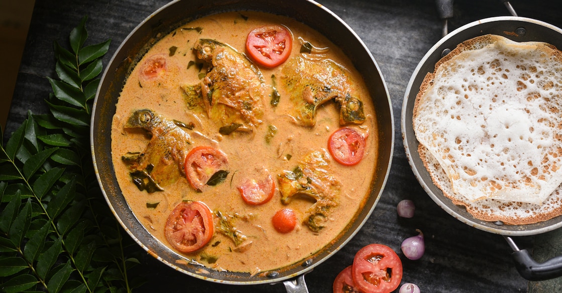 1900100941 Top view spicy Kerala Style Fish stew and Appam Fish Molee or Meen Moilee Indian food. Fish curry with coconut milk red chili, curry leaf, tomato. Asian cuisine. Delicious hot Bengali, Goan fish curry