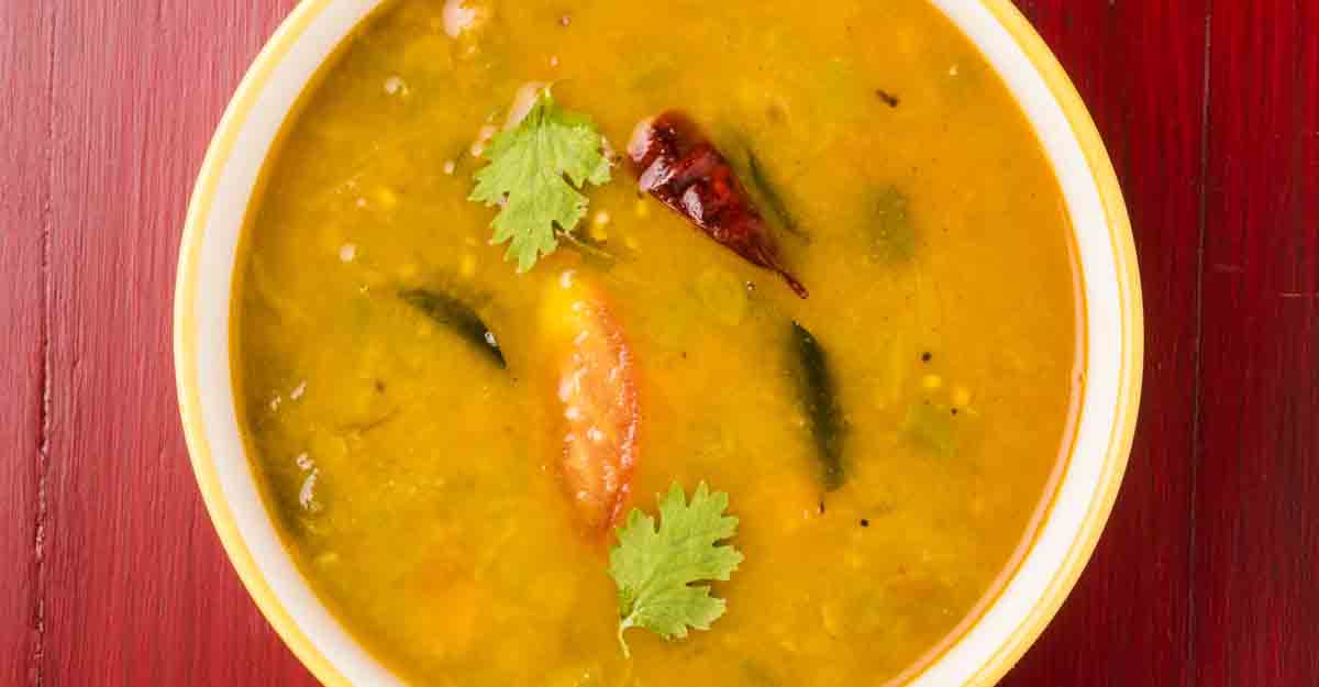 516598702 south indian vegetable sambar isolated on red wooden background