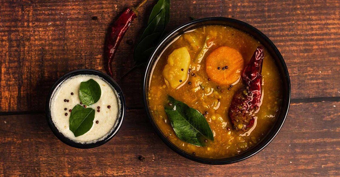 Sambar and coconut chutney arranged on black bowls on a wooden background. Photo: iStock/Jelina Preethi