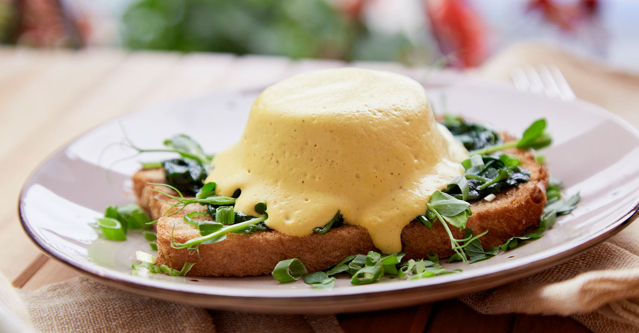 Vegan eggs Benedict dish with plant-based sauce, whole grain bread, smoked tofu, young onion, greens, pea sprouts outside. Photo: iStock/NataliaAlkema