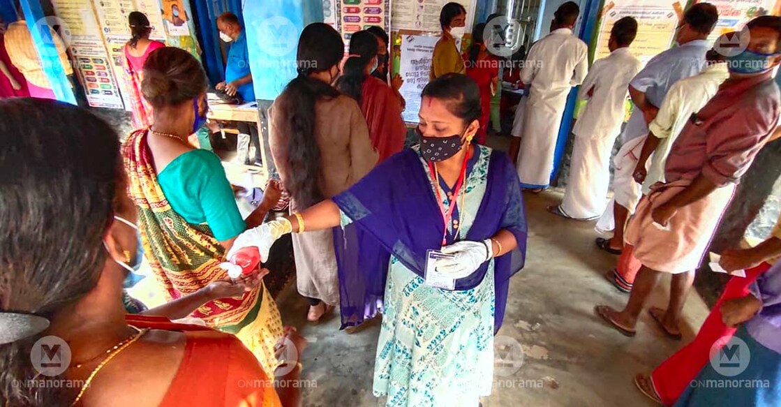 A polling official distributing sanitizer at a voting centre in Thrissur.