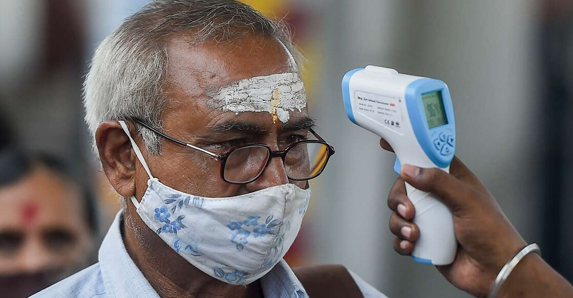 PTI10_09_2021_000138B A health worker checks body temperature of a traveler as a precaution against the coronavirus before allowing him to proceed at a railway station in Mumbai, Saturday, Oct. 9, 2021. (PTI Photo/Kunal Patil)