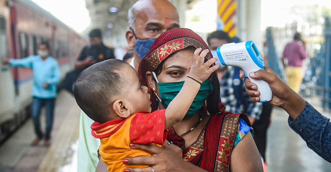 A BMC health worker conducts thermal screening of passengers at Dadar Railway Station in Mumbai on Nov. 17, 2021. Photo: PTI/Shashank Parade