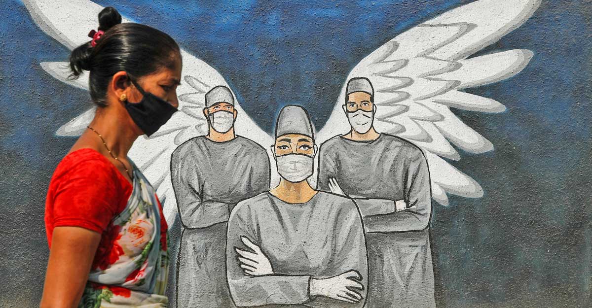 A woman wearing a protective mask walks past a graffiti amidst the spread of the coronavirus disease (COVID-19), on a street in Navi Mumbai, India, March 8, 2021. REUTERS/Francis Mascarenhas