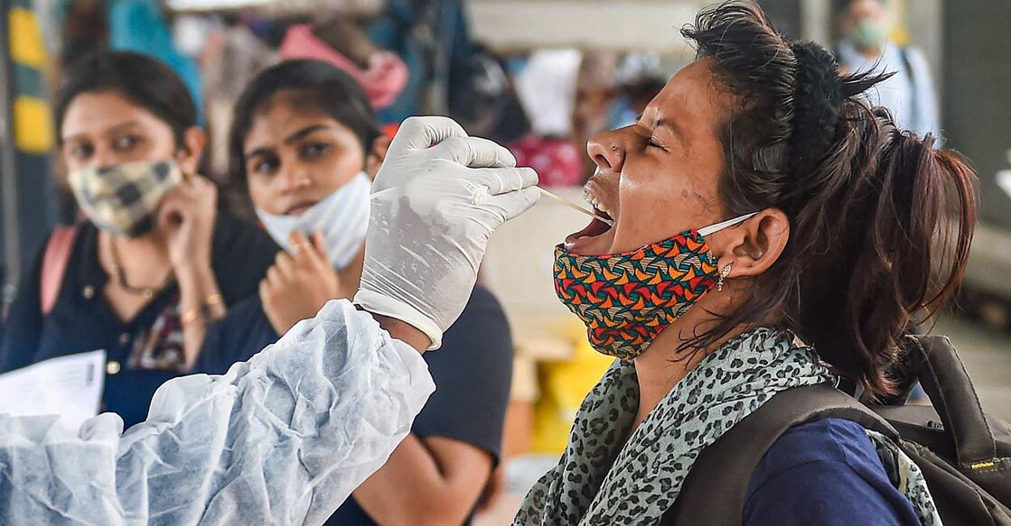 A health worker takes swab sample of a passenger for COVID-19 testing at Dadar railway station in Mumbai. PTI