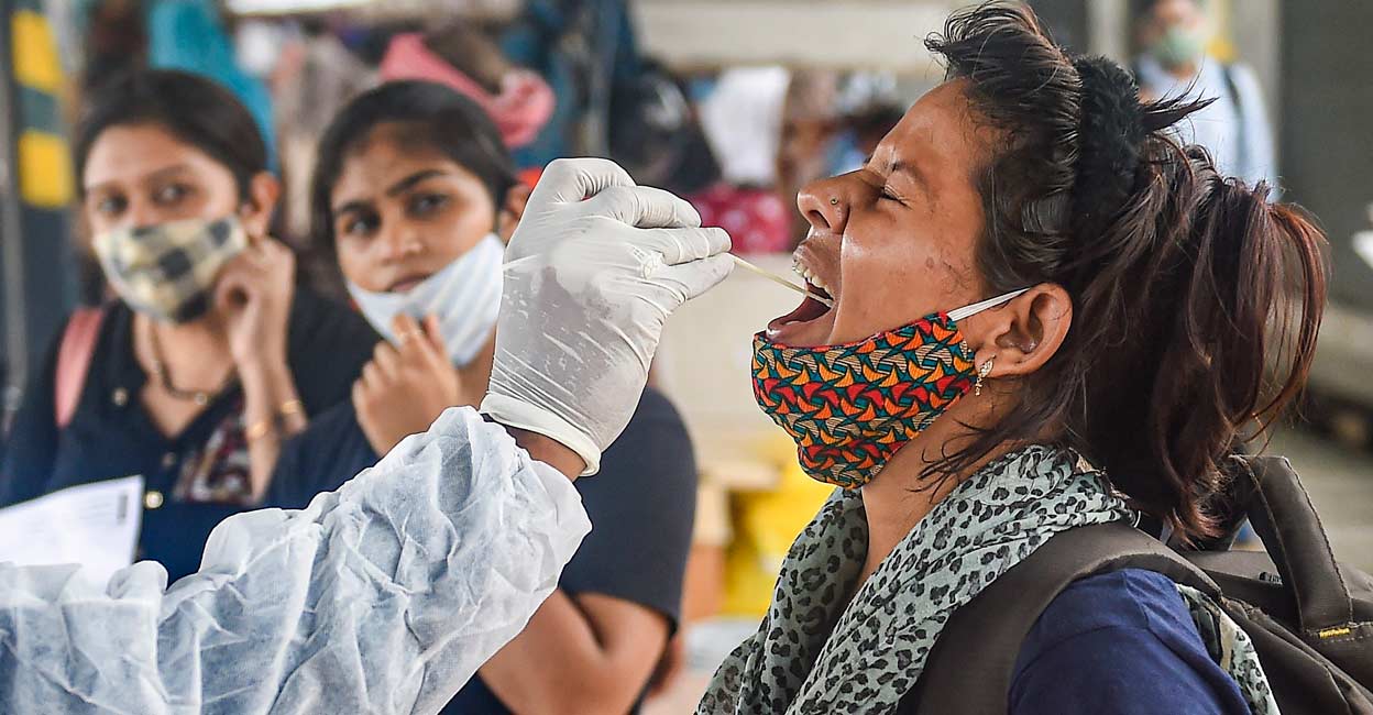 A health worker takes swab sample of a passenger for COVID-19 testing at Dadar railway station in Mumbai. PTI