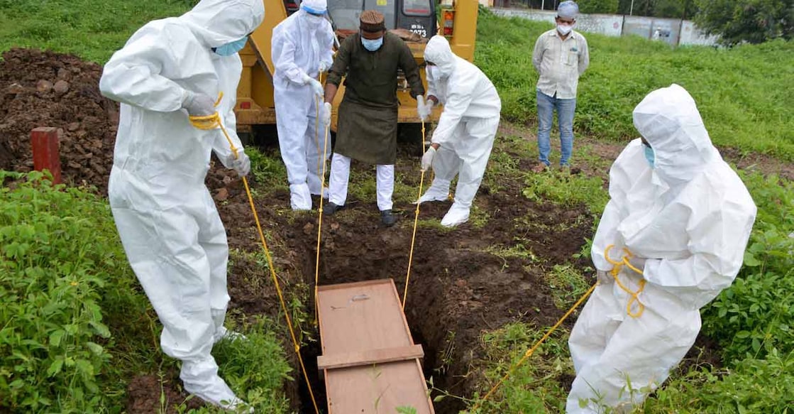 PTI07_02_2021_000049B Family members and relatives perform burial of a COVID-19 victim, at a graveyard in Karad. Photo: PTI