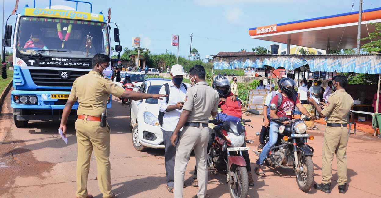 Police personnel check the COVID-19 test report of travellers at Talapady checkpost at Kerala-Karnataka border in Mangaluru. PTI
