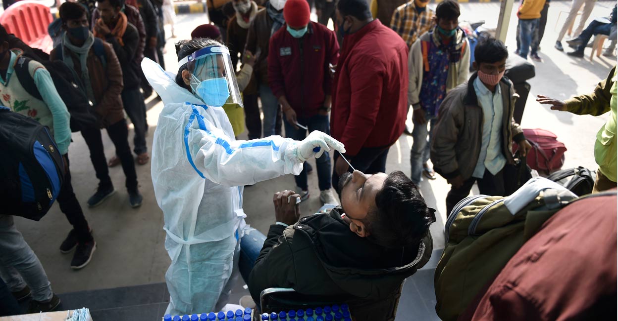 PTI12_31_2021_000033B health worker collects swab samples of passengers to conduct COVID-19 test, amid concern over rise in Omicron virus variant cases, at the Anand Vihar railway station near New Delhi, Friday. Photo: PTI