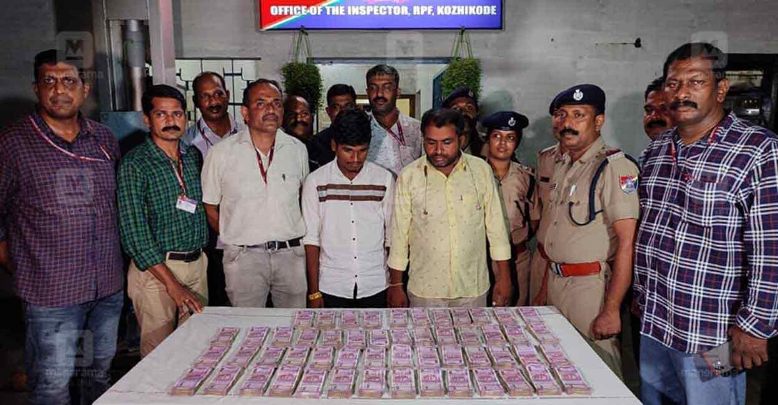 The accused pose, alongside an RPF team, in front of the hawala money that was seized.