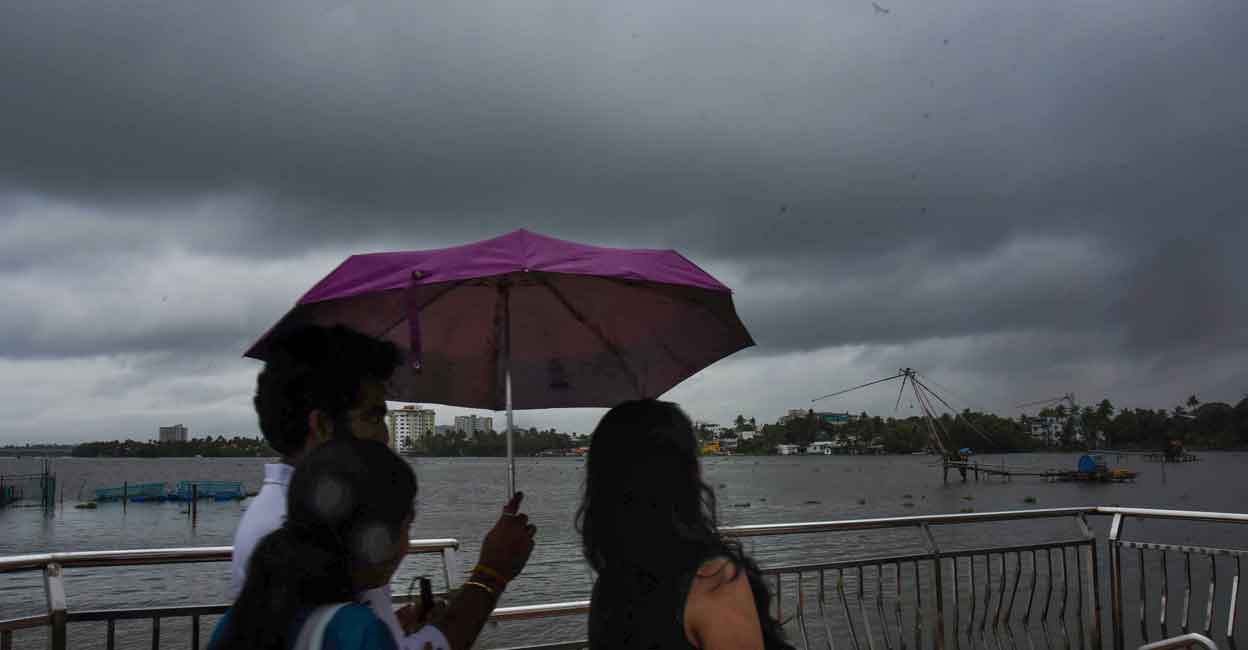 People use an umbrella to protect themselves from the rain, as dark clouds hover in the sky in Kochi, Sunday, May 22, 2022. Photo: PTI