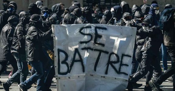 Protesters known as "black bloc" walk with a banner reading in French "to fight" during a demonstration on April 19, 2018 in Paris. Photo: AFP
