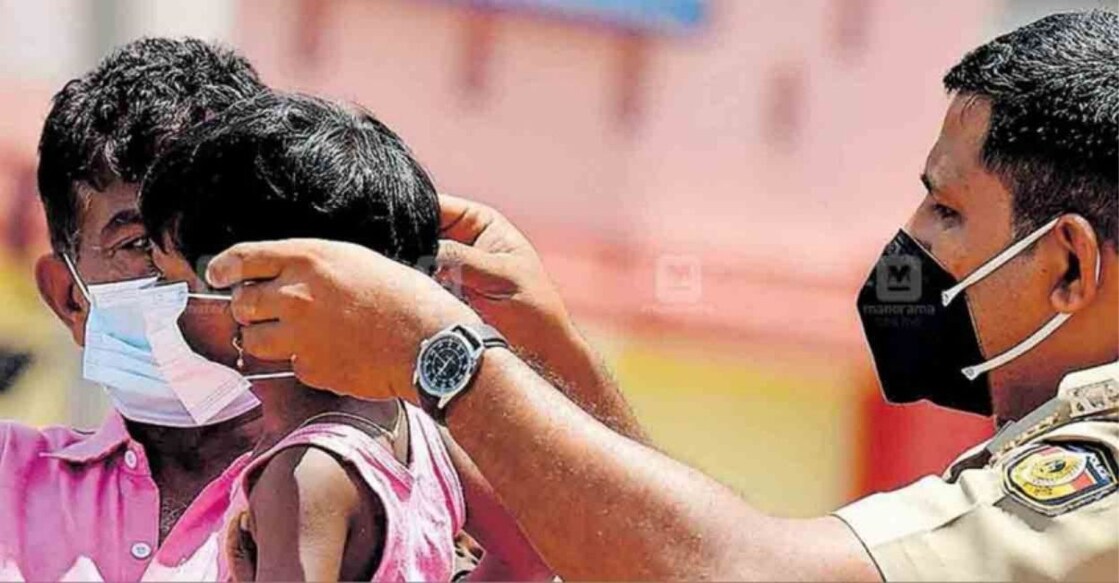 A police officer helps a little girl wear her mask. Photo: Manorama Online.