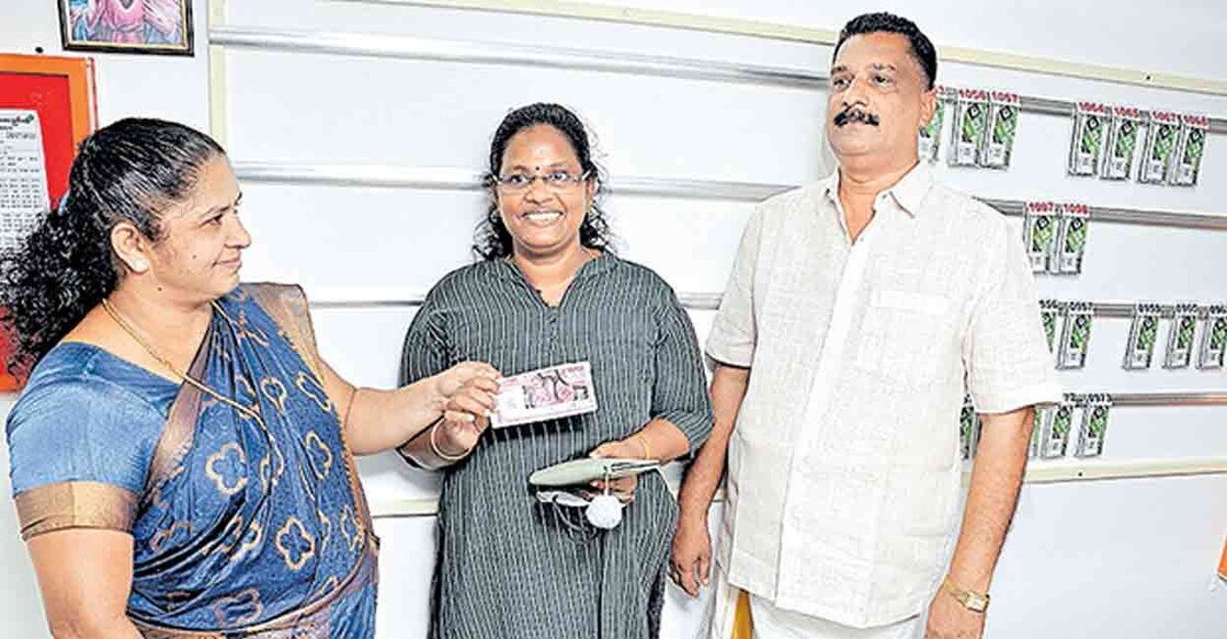 KG Sandhyamol (centre), the nurse who won the first prize of Rs 75 lakh in Sthree Sakthi Lottery, accepting the prize ticket from Sophie, wife of Sajan Thomas, owner of Vettikadu Lucky Centre at Mooppil Kadavu.  