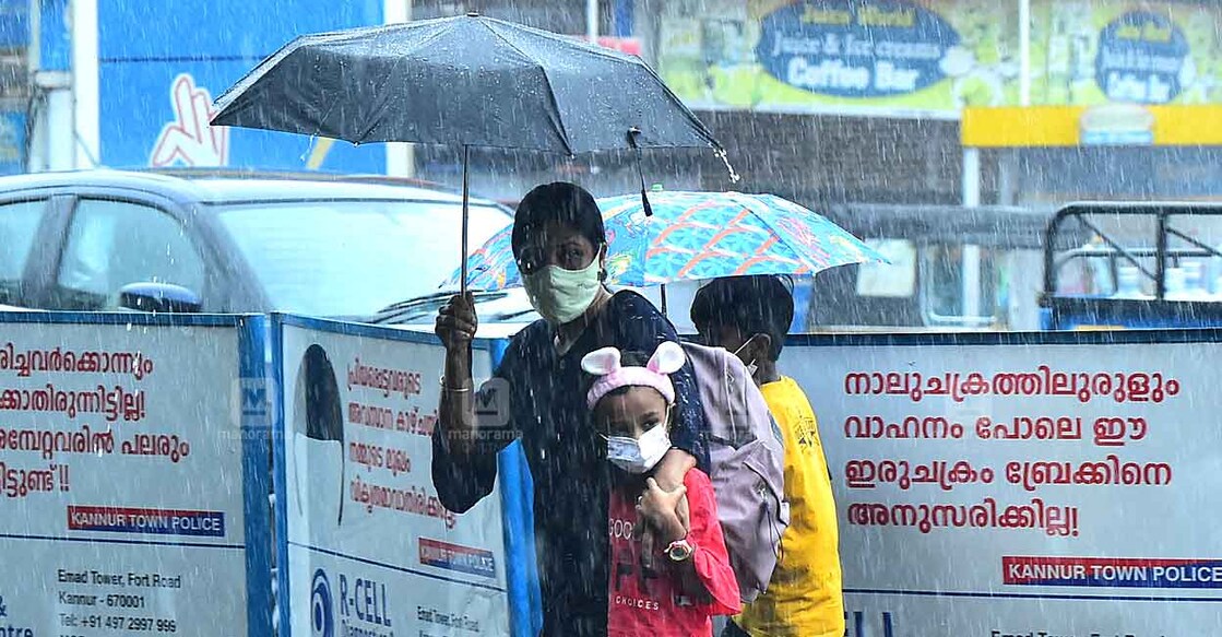 A family attempts to cross a road in Kannur amid heavy rains. Photo: Sameer A Hameed/Manorama