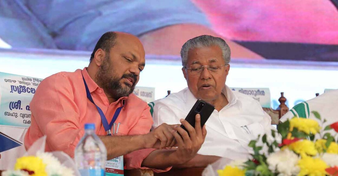 Chief Minister Pinarayi Vijayan looks at the mobile phone of his Cabinet colleague P. Rajeeve (Industry and Law) at the inauguration of the Samrambhaka Mahasangamam meet of investors and entrepreneurs, in Kochi on January 21, Saturday. Photo: Special arrangement