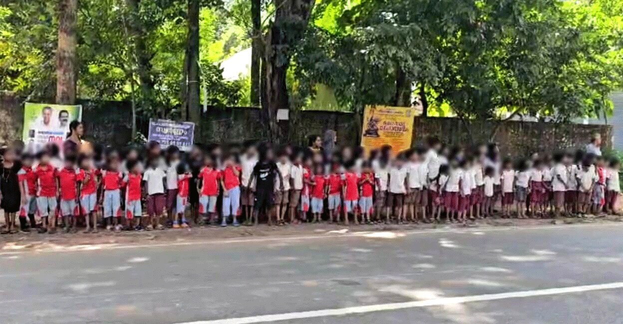 Students of Thuyyam School, Edappal wait on the roadside to greet the Nava Kerala Sadas bus Monday afternoon. Photo: Special arrangement