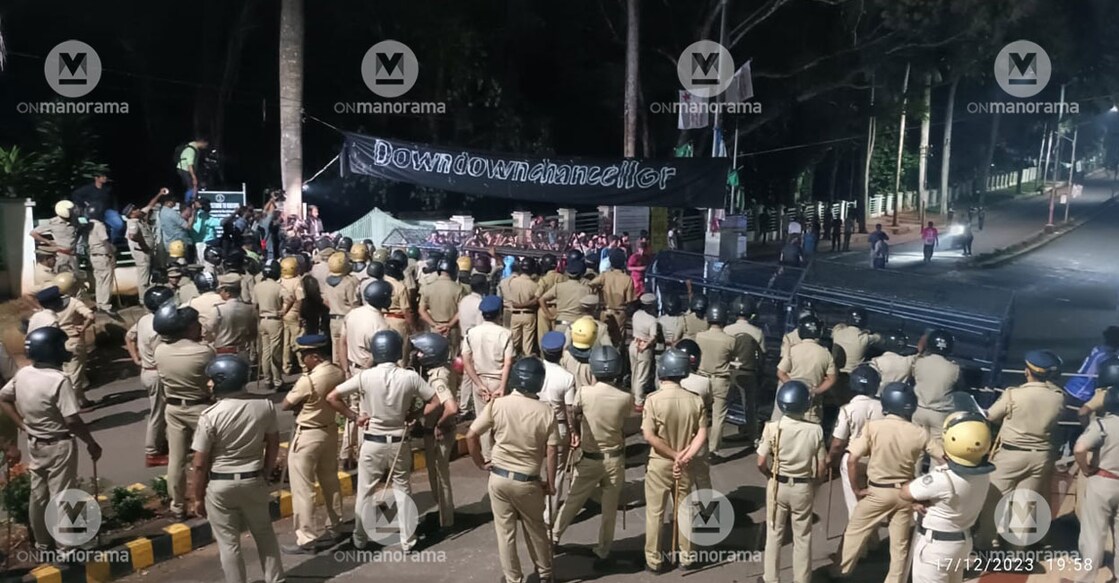 Police personnel watch as SFI raise a banner on the Calicut University campus Sunday night. Photo: Manorama