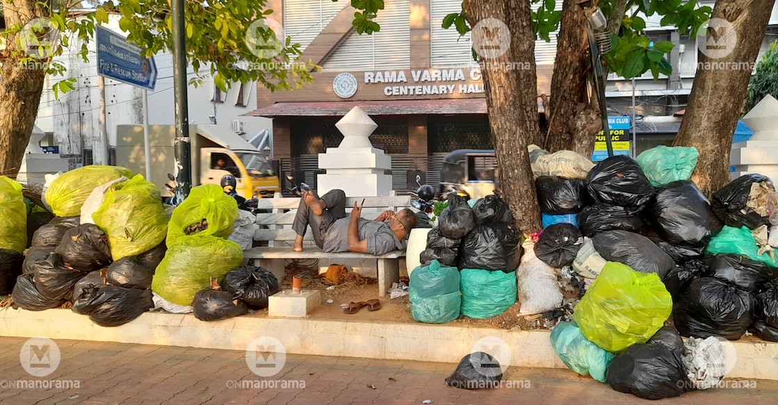 A man rests on a bench surrounded by a pile up of garbage bags near the Durbar Hall in Kochi. Photo: Josekutty Panackal/Manorama