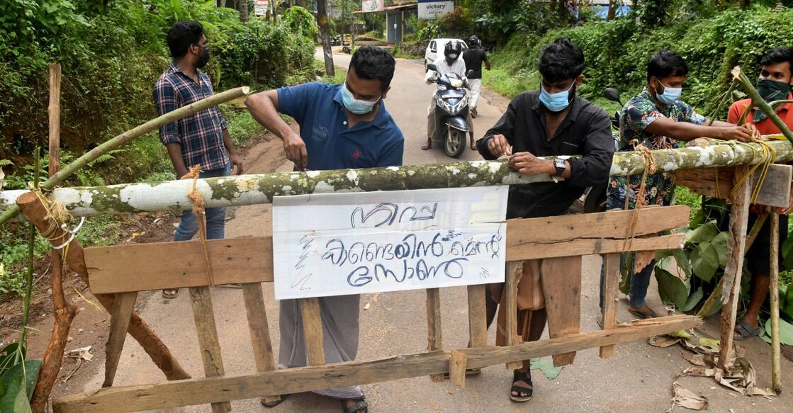 Residents fix a sign reading 'Nipah containment zone' on a barricade, put up to block a road after the authorities declared the area a containment zone, to prevent the spread of Nipah virus at Ayanchery village in Kozhikode. Photo: Reuters