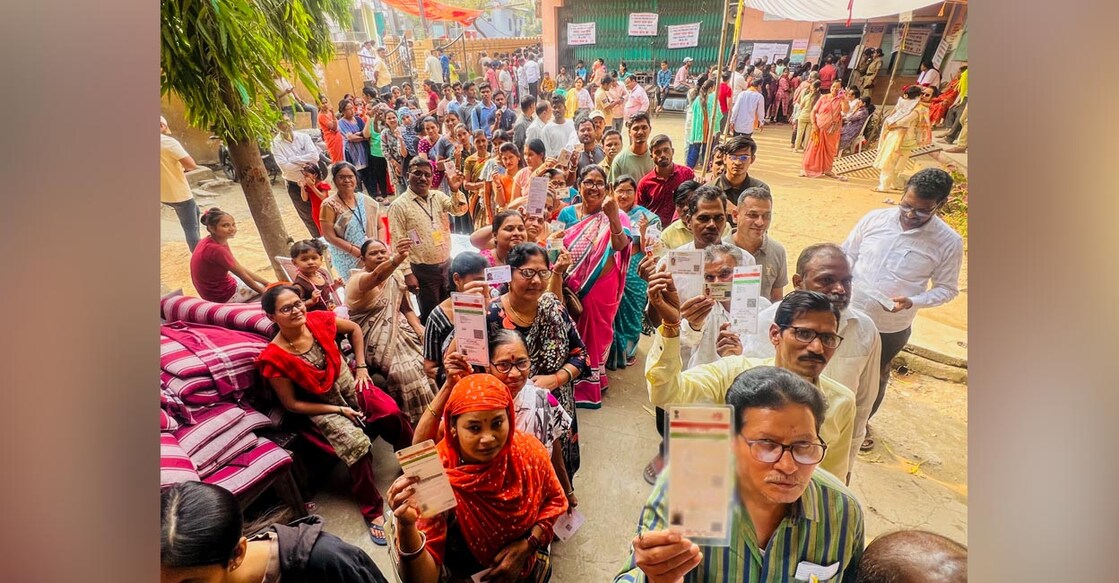 Voters show their identification cards as they wait in queues to cast their votes at a polling station during the Maharashtra Assembly elections in Nagpur, Maharashtra. Photo: PTI