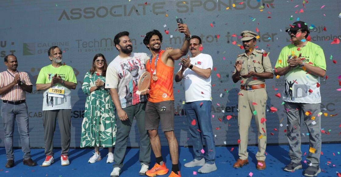 Joby Paul, who finished first in the 21-km open category of the second edition of GTECH Kerala Marathon at Infopark Kochi on February 11, Sunday, clicks a selfie with film actors Aparna Balamurali and Indrajith Sukumaran. Photo: Special Arrangement