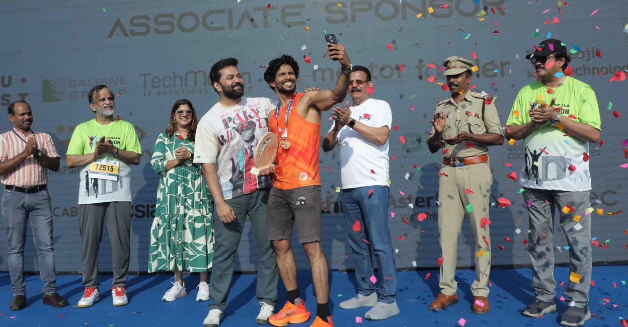 Joby Paul, who finished first in the 21-km open category of the second edition of GTECH Kerala Marathon at Infopark Kochi on February 11, Sunday, clicks a selfie with film actors Aparna Balamurali and Indrajith Sukumaran. Photo: Special Arrangement