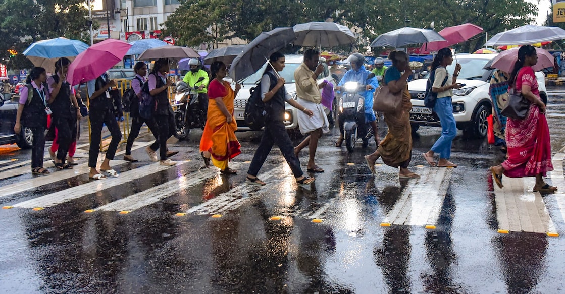 Pedestrians hold umbrellas as they cross a street in Kochi on a rainy Wednesday. Photo: PTI