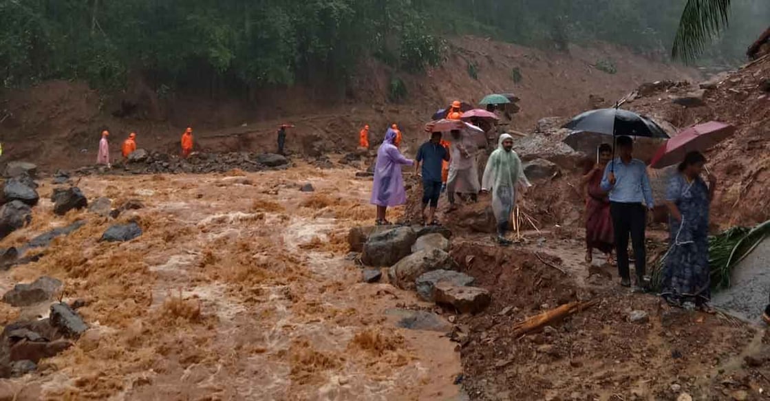 Kozhikode District Collector Snehil Kumar Singh (blue shirt) and officials move along a flooded area during a visit to landslide-hit Vilangad Wednesday evening. Photo: Special arrangement