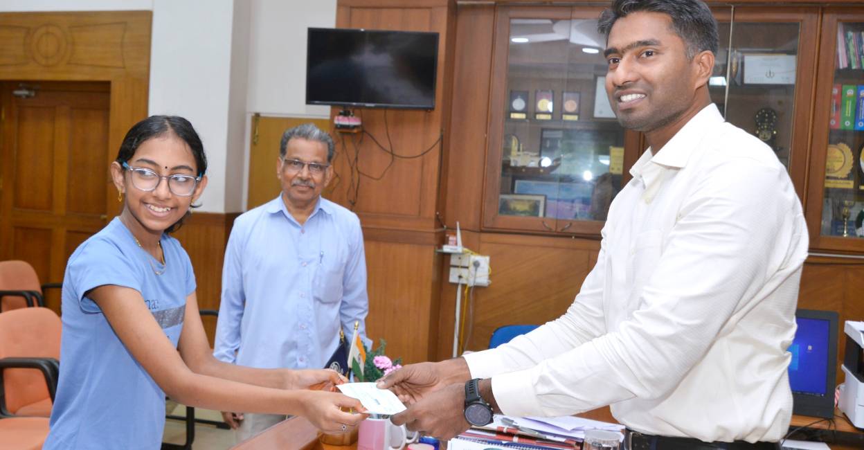 Diya hands over cheque to Thrissur District Collector Arjun Pandian. Photo: Special Arrangement