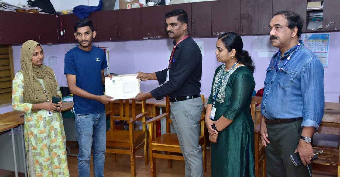 DEO R Sarathchandran handing over the certificates to Muhammed Nabeel at the relief camp in Government High School, Meppadi on Wednesday. Photo: Special arrangement