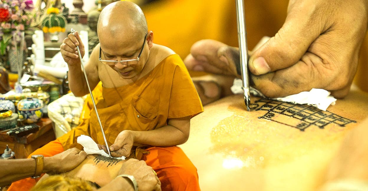Tattooing-bamboo-add Monk making a traditional Yantra tattoo in Nakhon Chai, Thailand. Photo: Shutterstock/ De Visu