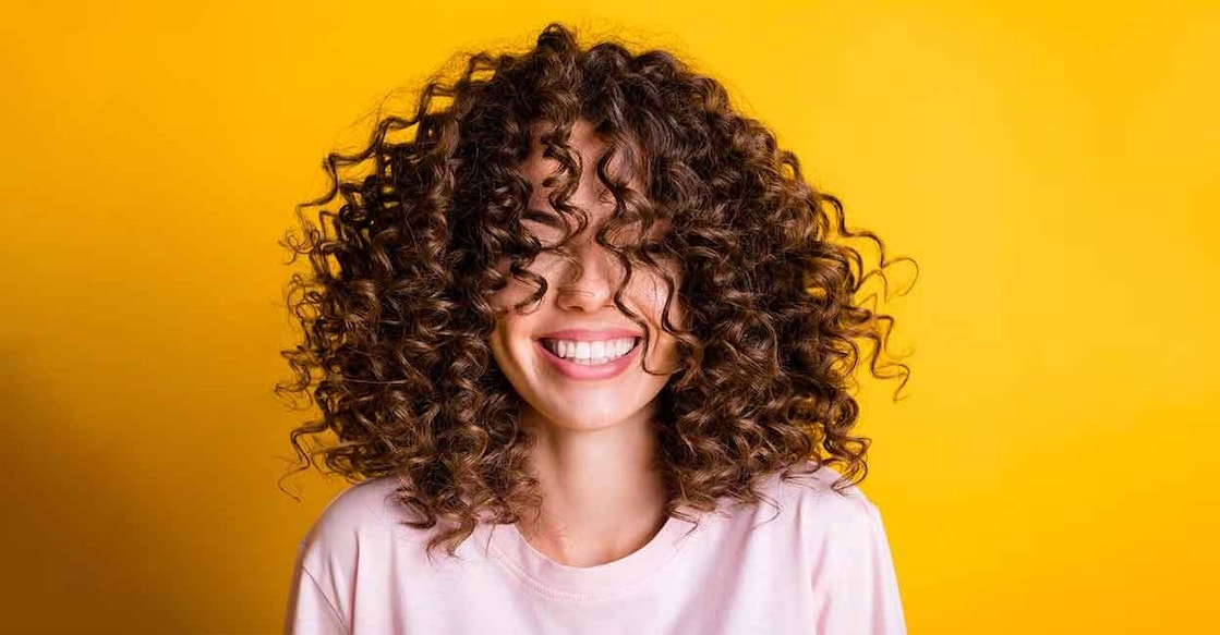 curly-hair Curly hair naturally attracts moisture and dirt from the environment. Photo: Shutterstock/Samborskyi