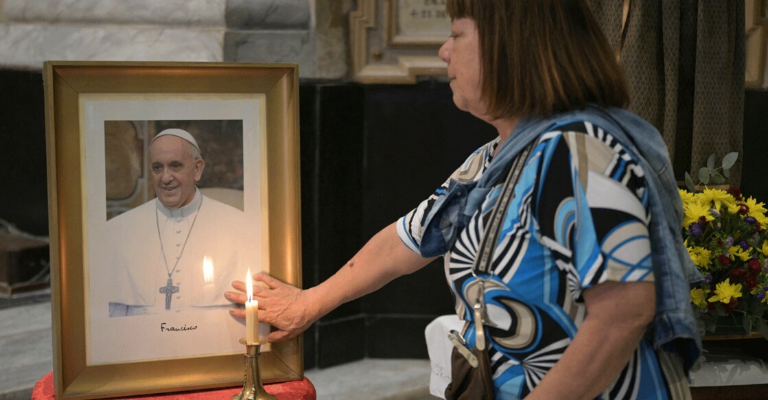 A faithful touches a portrait of Pope Francis during a mass at the Basilica San Jose de Flores to pray for his health. Photo: AFP