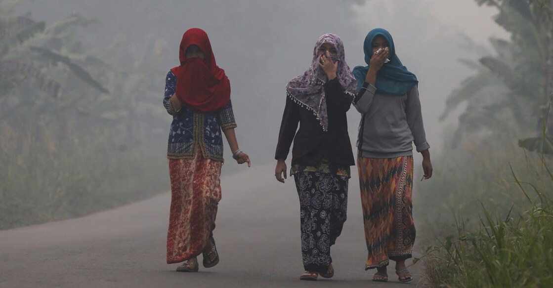 Villagers walk on a street as the haze shrouds Pulau Mentaro village in Muaro Jambi, on the Indonesian island of Sumatra. REUTERS/Beawiharta
