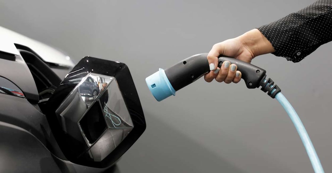 A woman holds a cable to charge a Renault Kangoo ZE electric utility vehicle. REUTERS/Eric Gaillard/file