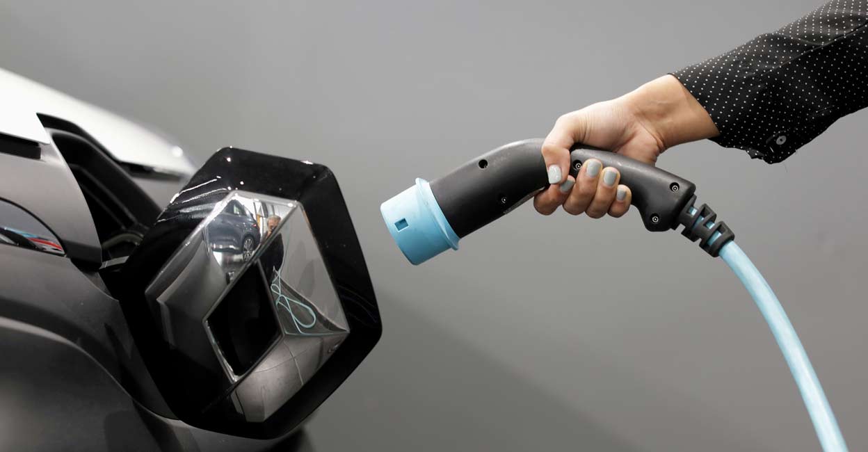 A woman holds a cable to charge a Renault Kangoo ZE electric utility vehicle. REUTERS/Eric Gaillard/file