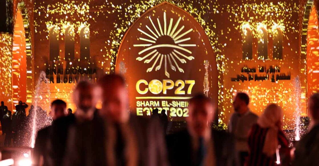CLIMATE-UN People pass in front of a wall lit with the sign of COP27 as the climate summit takes place, at the Green Zone in Sharm el-Sheikh on November 10. Photo: Reuters/Mohamed Abd El Ghany