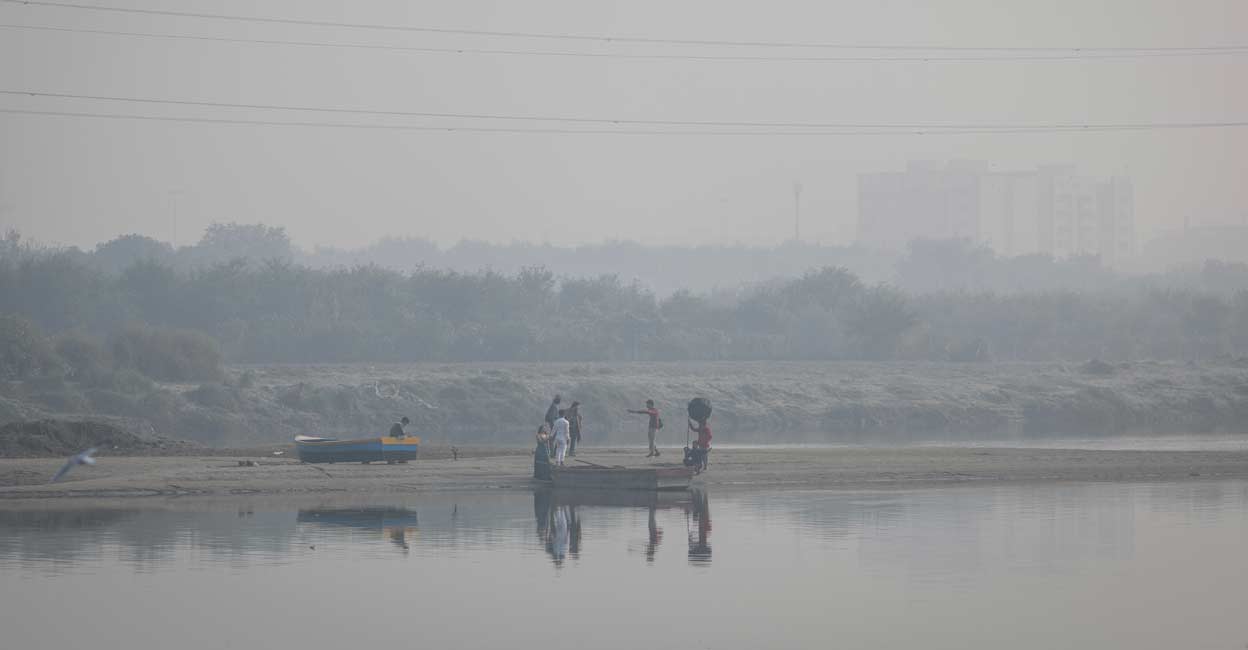 A couple poses for a photo on the banks of Yamuna river on a smoggy morning in the old quarters of Delhi. Reuters/Adnan Abidi/File Photo