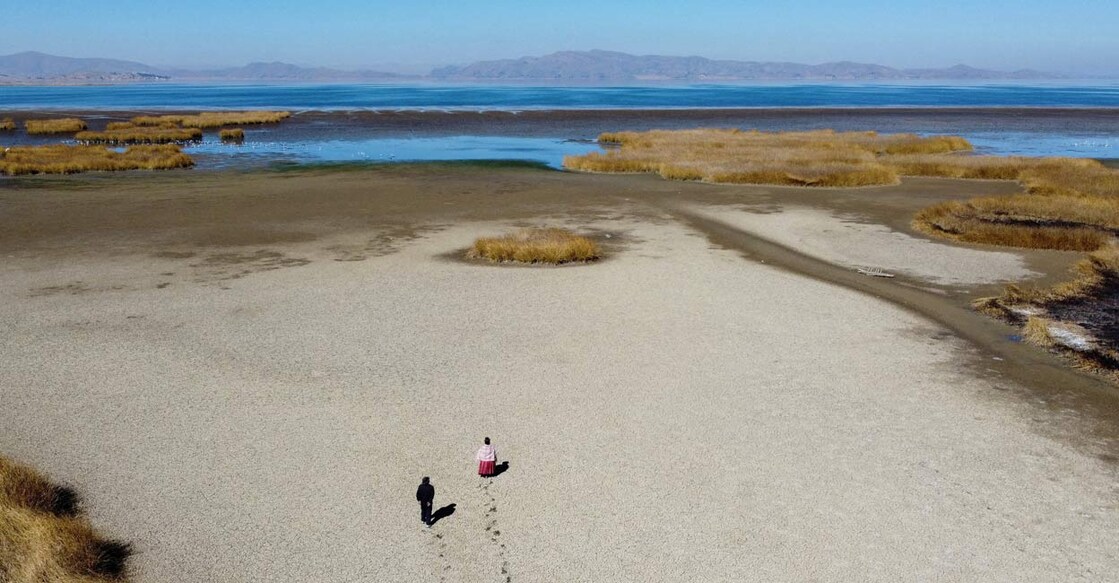 WEATHER-ELNINO-WMO Gabriel Flores and Isabel Apaza walk on the dry cracked bed near the shore of Lake Titicaca in drought season in Huarina, Bolivia. Photo: Reuters/Claudia Morales/File