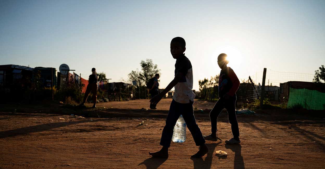 Young residents carry water home after filling up a bottle at a community filling station in the informal settlement of Kanana. Photo: Ihsaan Haffejee/File