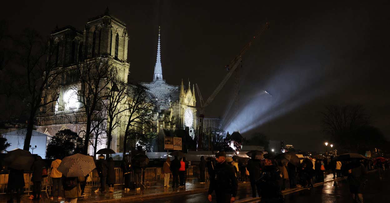 FRANCE-NOTREDAME People protect themselves from the rain under umbrellas as they stand near the Notre-Dame de Paris Cathedral. Photo: REUTERS/Kevin Coombs