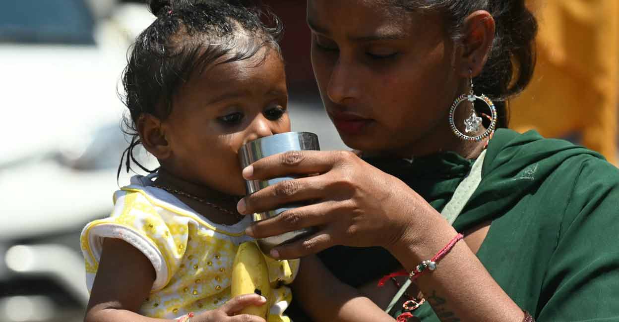 A mother helps her daughter to drink water during a hot summer day in Amritsar. File Photo: Nanu / AFP