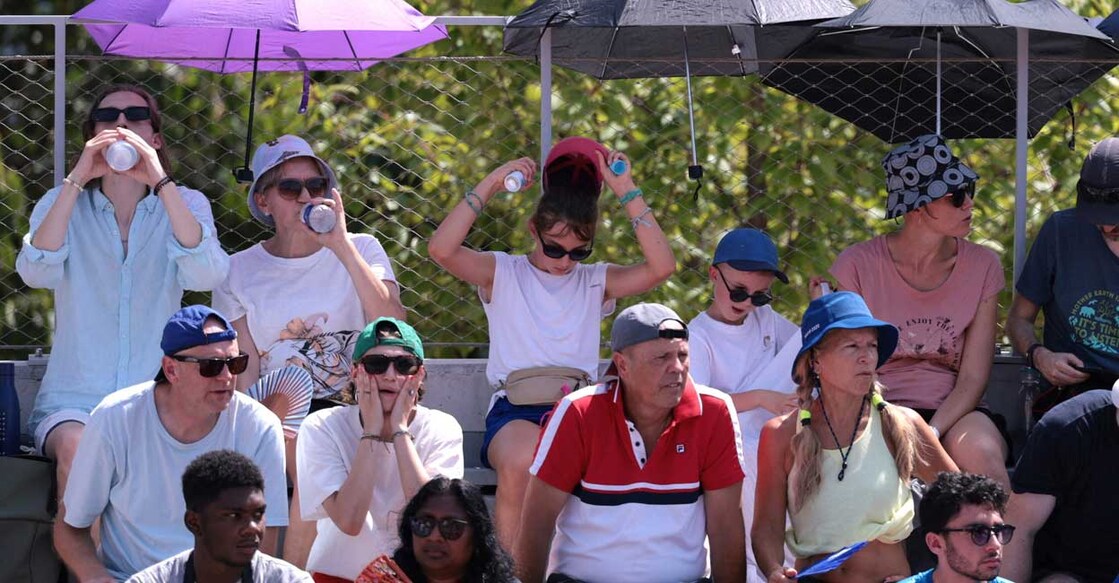 Spectators use umbrellas to protect themselves from the sun during the match between Lorenzo Musetti of Italy and Mariano Navone of Argentina during Men's Singles Second Round at Roland-Garros Stadium, Paris. Singles players allowed 10-minute break due to extreme heat. Photo: REUTERS/Claudia Greco