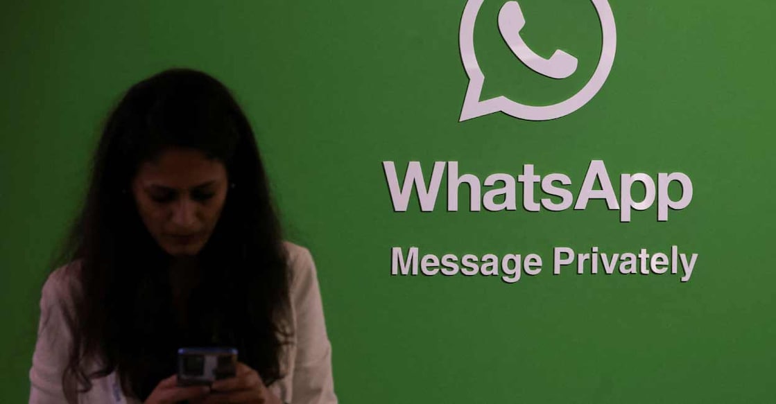 A woman uses her phone next to a logo of the WhatsApp application during Global Fintech Fest in Mumbai. Photo: REUTERS/Francis Mascarenhas/File