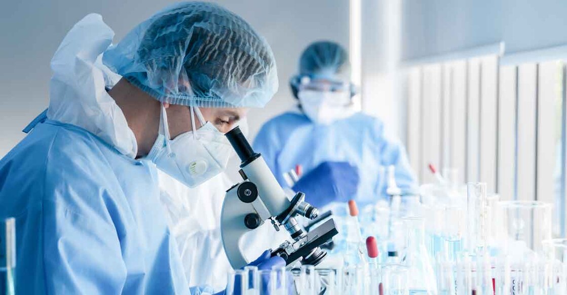 Scientist looking through a microscope: Mongkolchon Akesin / Shutterstock
