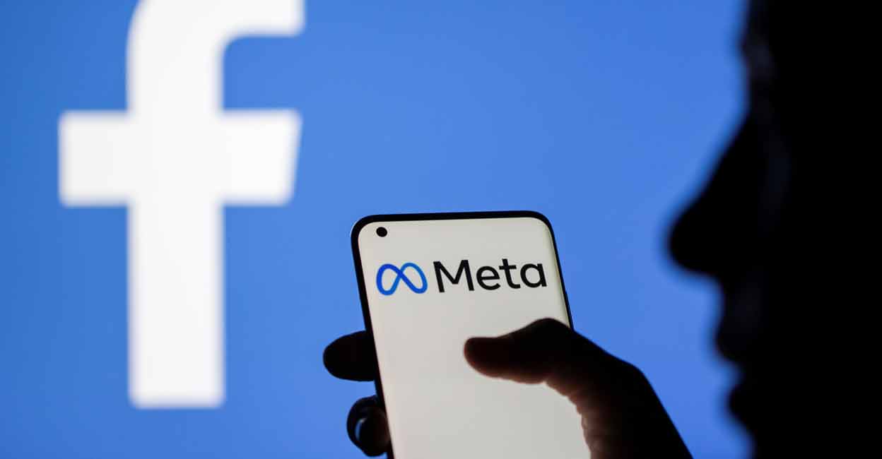 A woman holds a smartphone with Meta logo on it in front of a displayed Facebook logo in this illustration taken, October 28, 2021. REUTERS/Dado Ruvic/Illustration