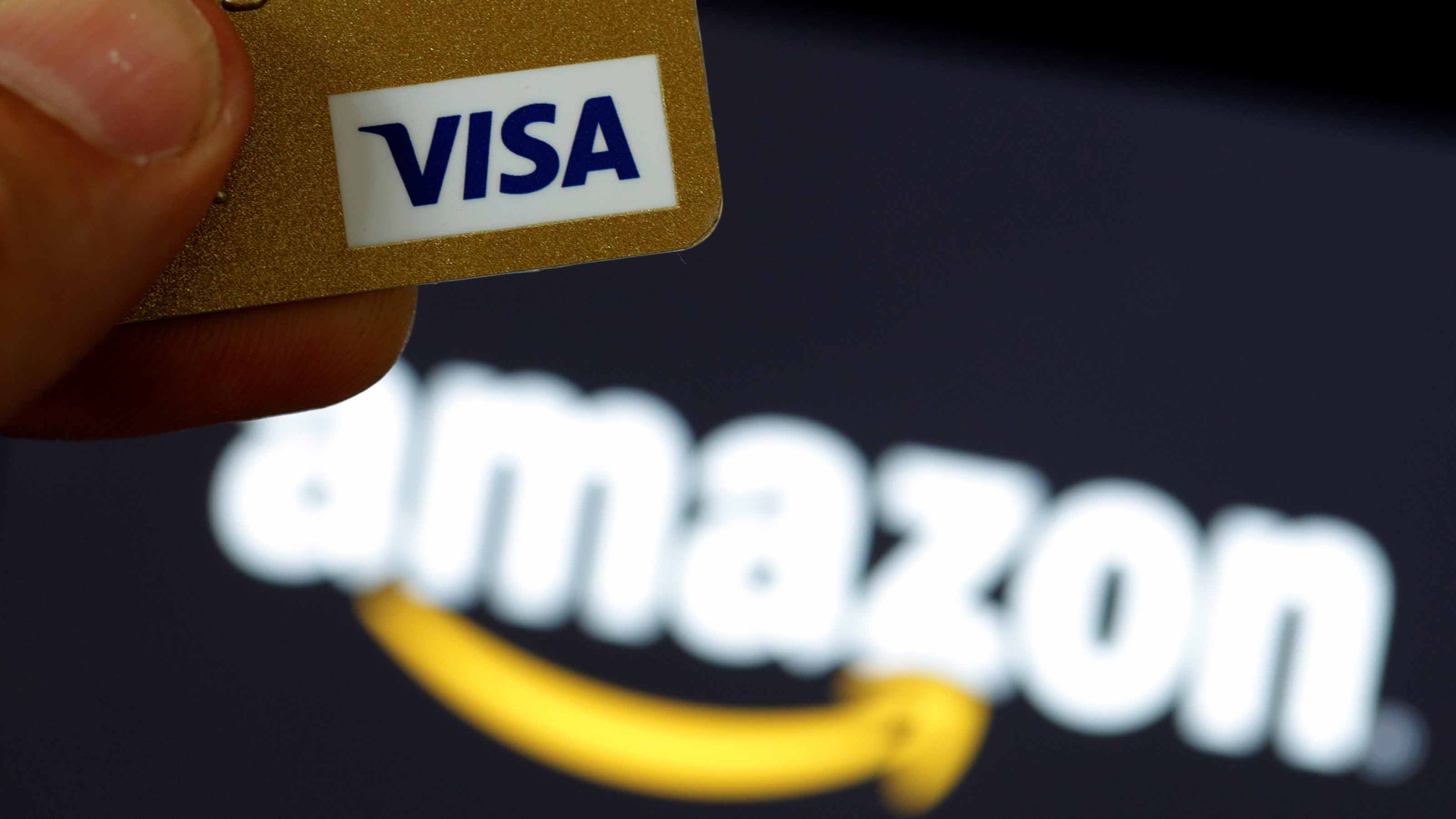 GLOBAL-BANKS A visa credit card is held in front of an Amazon logo in this picture illustration taken September 6, 2017. Photo: REUTERS/Philippe Wojazer/Illustration